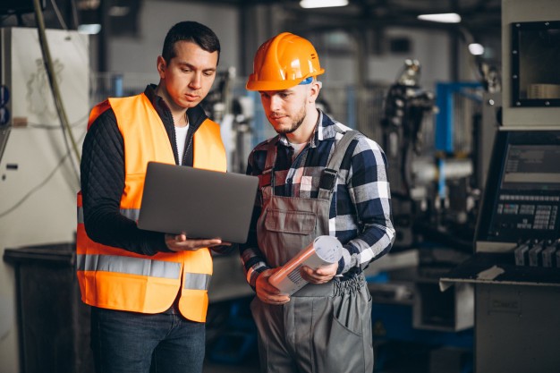 Two Factory worker talking while wearing safety hat and vest